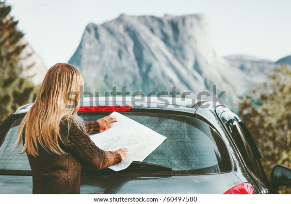 Woman car driver with map on road trip\
planning journey route in Norway Travel Lifestyle concept adventure\
vacations outdoor mountains on\
background