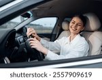 Woman, car, driver, steering wheel, smiling, looking at camera a woman is seated in the driver