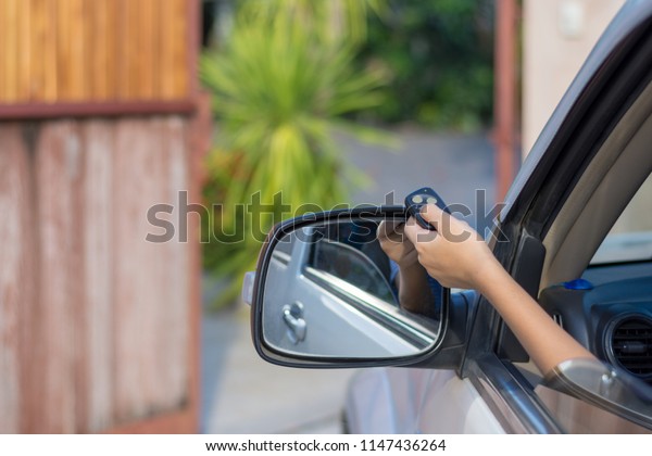 Woman in\
car, hand holding and using remote control to open the automatic\
gate. security system and save time\
concept.