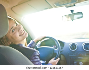 woman in car indoor keeps wheel turning around smiling looking at passengers in back seat idea taxi driver talking to police companion companion who asks for directions right to drive Documents exam