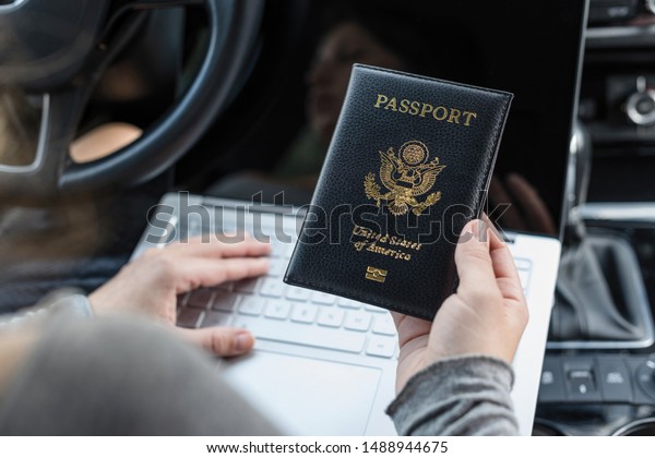 Woman in the car with laptop and american\
passport. Travel concept.