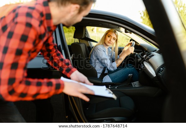 Woman in car\
looks on instructor with\
checklist