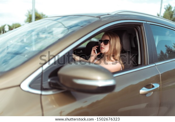 A\
woman in the car, makes a phone call, stands in parking lot of a\
shopping center. A long traffic jam, a call to her husband or\
parents with children. Warns that delayed on the\
road.