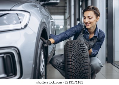 Woman car mechanic changing tires at car service - Powered by Shutterstock