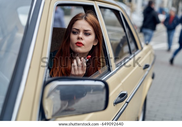 Woman in the car, the woman paints the lips\
in the car                              \
