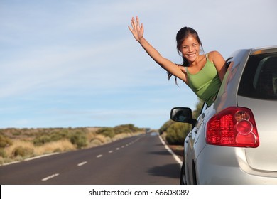 Woman in car road trip waving out the window smiling.  Image from Teide, Tenerife. Mixed race Asian / Caucasian woman.