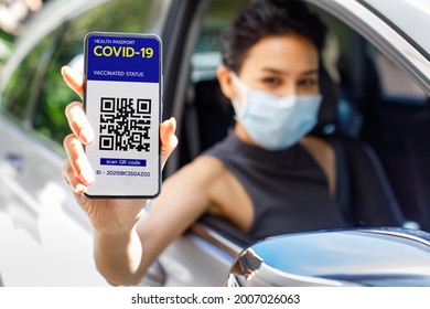 Woman In Car Show Screen Of Smartphone With Covid-19 Or Coronavirus Health Passport Vaccinated Status And QR Code Sign To Show She Already Get Vaccine. Herd Immunity Concept.