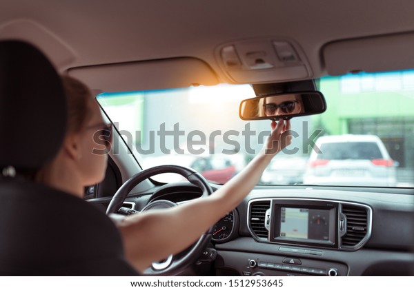 woman car\
summer city parking lot, looks rear view mirror, parks reverse,\
looks rear seat, checks children in back rows of seat. Background\
car interior, steering wheel navigation\
display
