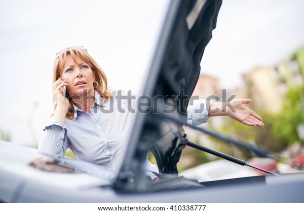 Woman with car trouble in the middle of the\
street, after car\
breakdown