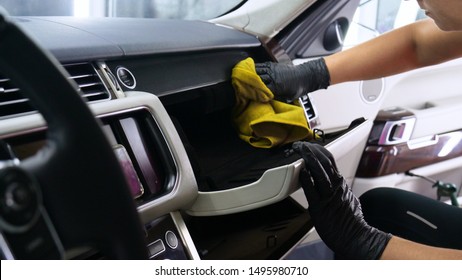 A woman at a car wash does a full dry-cleaning of all parts of a car using special chemistry, cloths, sponges and brushes. Concept of: Full car cleaning, Dry cleaning, Professional service. Car, Work.