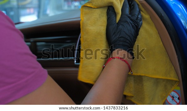 A woman at a car wash does a full dry-cleaning of\
all parts of a car using special chemistry, cloths, sponges and\
brushes. Concept of: Full car cleaning, Dry cleaning, Professional\
service. Car, Work.