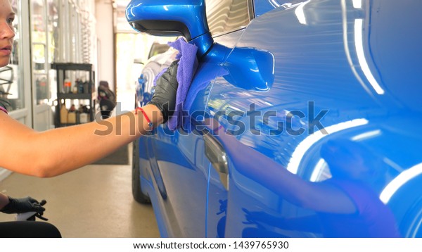 A woman at a car wash does a full dry-cleaning of
all parts of a car using special chemistry, cloths, sponges and
brushes. Concept of: Full car cleaning, Dry cleaning, Professional
service. Car, Work.