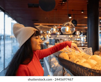 A woman carefully selects bread at an indoor market, illuminated by warm lighting. - Powered by Shutterstock