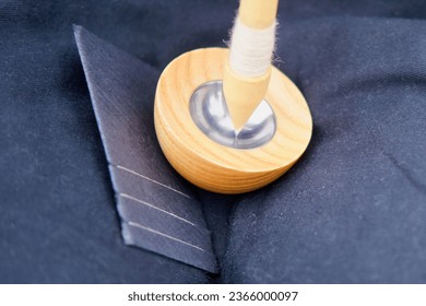 The woman carefully spins the wool into thread using a drop spindle, showcasing her skill in the craft of spinning. - Powered by Shutterstock