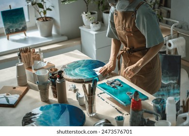 Woman carefully thoroughly wiping finished epoxy resin painting from dust and stains. Female artist hands performs final stages of creative work, taking care of outer layer of dried liquid picture. - Powered by Shutterstock