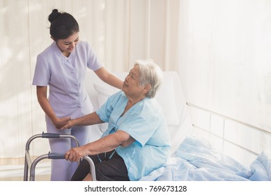 woman caregiver and elderly patient on examination couch. Happy nurse holding hand of senior to help senior patient. female nurse supporting senior disabled woman with walker at hospital. Health care  - Powered by Shutterstock