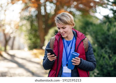 Woman Caregiver, Nurse Or Healthcare Worker Outdoors On The Way To Work, Using Smartphone.