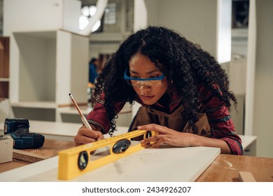 Woman carpenter drills a hole with an electrical drill. Carpenter at work at industrial job site. - Powered by Shutterstock