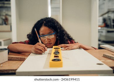 Woman carpenter drills a hole with an electrical drill. Carpenter at work at industrial job site. - Powered by Shutterstock