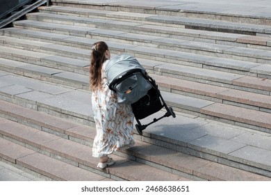 Woman carries a stroller up the stairs, mother with baby pram on city street - Powered by Shutterstock