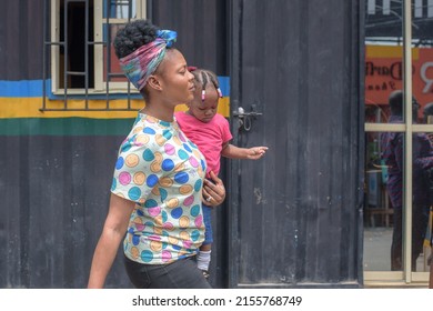 A woman carrying a child walks across a police post in Computer Village as people go about their day and business, Lagos, NIGERIA, May 7 2022. Nigeria's Economy as Inflation rises