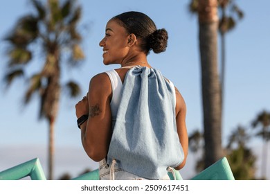 Woman carrying drawstring bag at the beach, pastel blue accessory - Powered by Shutterstock