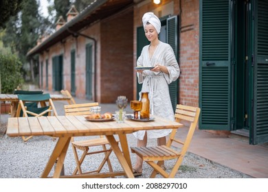 Woman Carrying Food To Table For Breakfast During Resting In Hotel At Morning Time. Concept Of Weekend, Tourism And Vacation. Young Caucasian Woman Wearing Bathrobe And Wrapped Bath Towel On Head