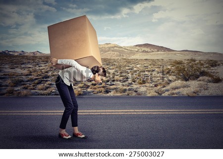 Woman carrying on her shoulders a large box 