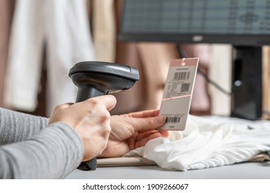 Woman cashier, seller scanning and reading  barcode from clothes using barcode scanner in female clothing store.  
