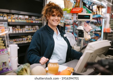 Woman Cashier At Supermarket. Cash Register Clerk Smiling At Camera.