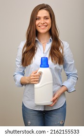 Woman In Casual Clothes Blue Shirt And Jeans Holding Laundry Detergent In White Big Bottle.