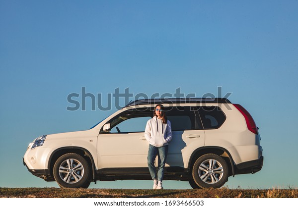 woman in\
casual clothes standing near white suv\
car