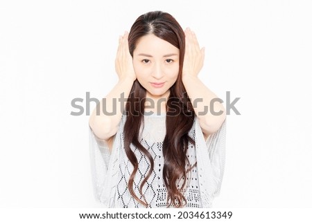 A woman in casual clothes that closes her ears