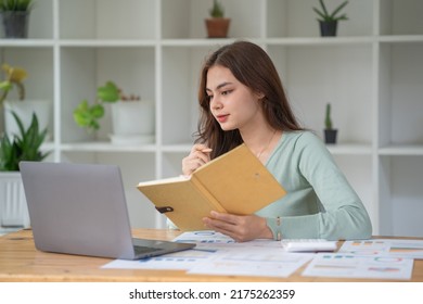 Woman In Casual Clothing Holding Note Book And Working On Laptop Computer 