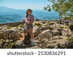 A woman in casual outdoor attire navigates a rocky terrain with a map. The image captures a sense of adventure and exploration, set against a breathtaking natural backdrop.