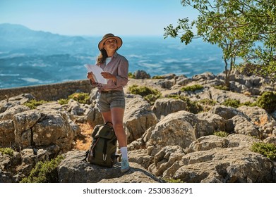 A woman in casual outdoor attire navigates a rocky terrain with a map. The image captures a sense of adventure and exploration, set against a breathtaking natural backdrop. - Powered by Shutterstock