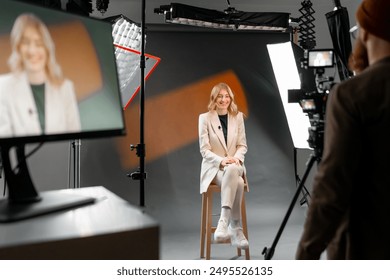 Woman in casual outfit sitting in professional video recording studio with camera and lights - Powered by Shutterstock