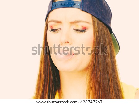 Woman casual style teen girl cap on head colorful makeup doing bubble with chewing gum closeup. Youth style