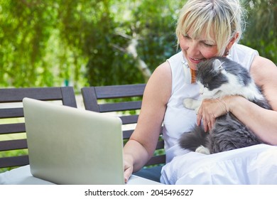 Woman With Cat On Laptop PC During Zoom Video Chat Meeting During Leisure Time In The Garden