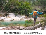 Woman catches balance on a log, A woman with a backpack is walking along the trunk of a fallen tree, A girl crosses a river on a log,  A girl walks through the woods.