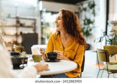 Woman catching up with friends over coffee in a restaurant, chatting and enjoying the lively atmosphere. Happy young, Caucasian woman socializing with a group of people in a cafe. - Powered by Shutterstock