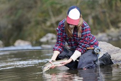 Woman Catching Rainbow Trout Fly In River