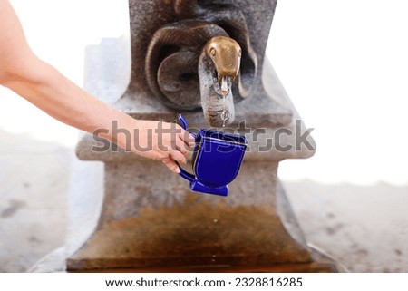 Woman catching a water from hot mineral spring in Karlovy Vary in special mug