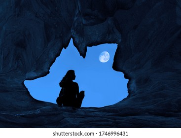 Woman Caver Spelunker exploring inside of a Dark Cave. female sitting at the edge of the cave hole.wolf shaped of cave hole.Silhouette of a girl standing in front of the entrance to the cave.full moon