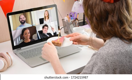 Woman celebrating her birthday through video call virtual party with friends. Lits and blows out candle. Authentic decorated home workplace. Coronavirus outbreak 2020. - Powered by Shutterstock