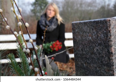 Woman in cemetery sits at a grave in deep sadness about death and loss - Shutterstock ID 1064484344