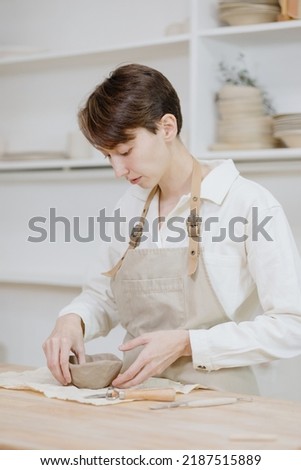 Similar – Young female sitting by table and making clay or ceramic mug