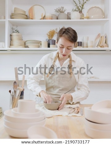 Similar – Young female sitting by table and making clay or ceramic mug