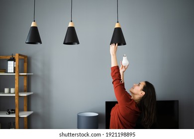 Woman Changing Broken Light Bulb To LED