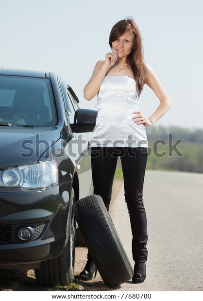 Woman changing car wheel at\
road